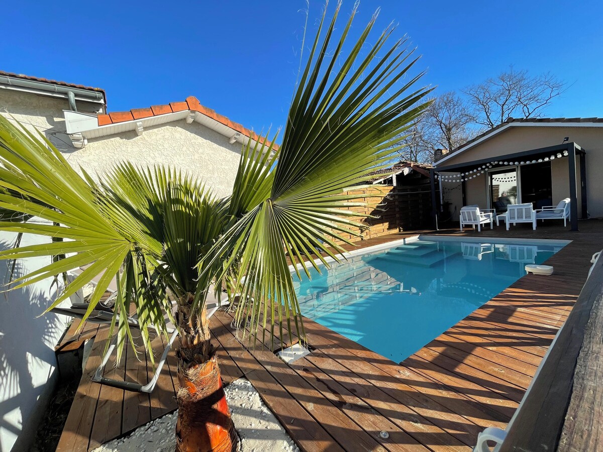 Piscine avec palmier et terrasse en bois sous ciel bleu — La Maison des Coccinelles, Gujan-Mestras