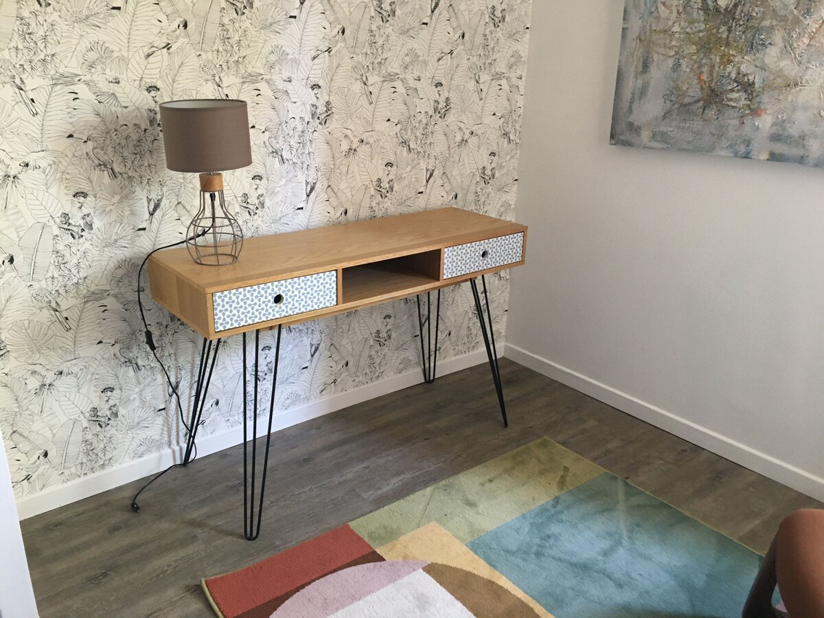 Espace de travail dédié avec bureau en bois sur pieds épingle, lampe et papier peint fleuri — La Maison des Coccinelles